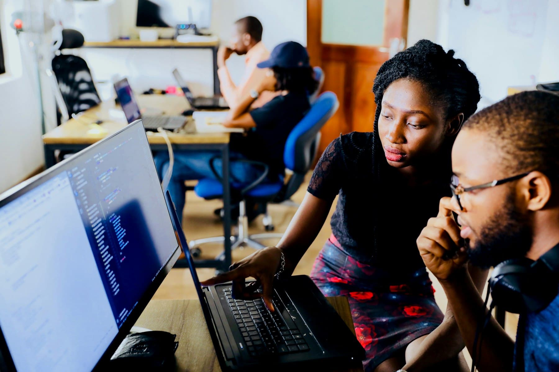 Two engineers reviewing a platform on a monitor and a laptop.