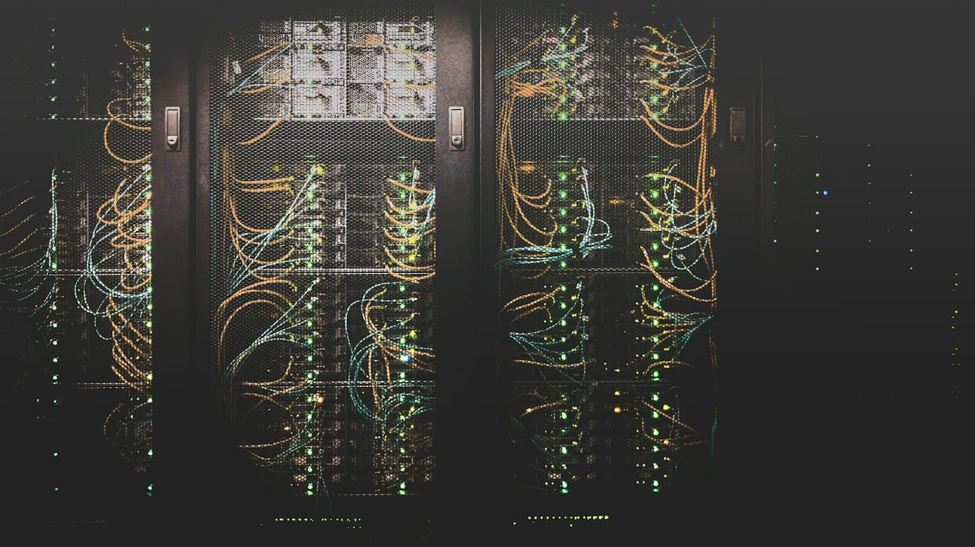 Server racks with illuminated network cabling in a data hall.